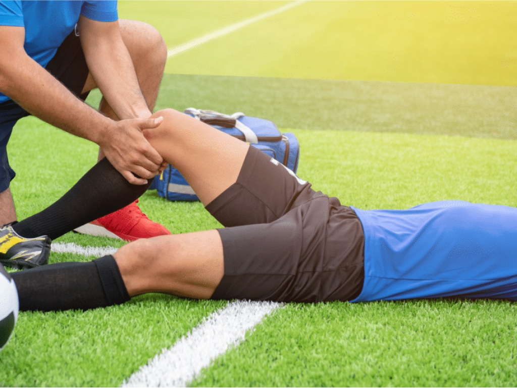 Erstversorgung von verletztem Fußballer auf dem Spielfeld
