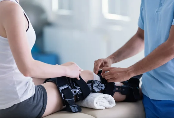Arzt post-OP bei Untersuchung Knie-Gelenk nach Knie-OP